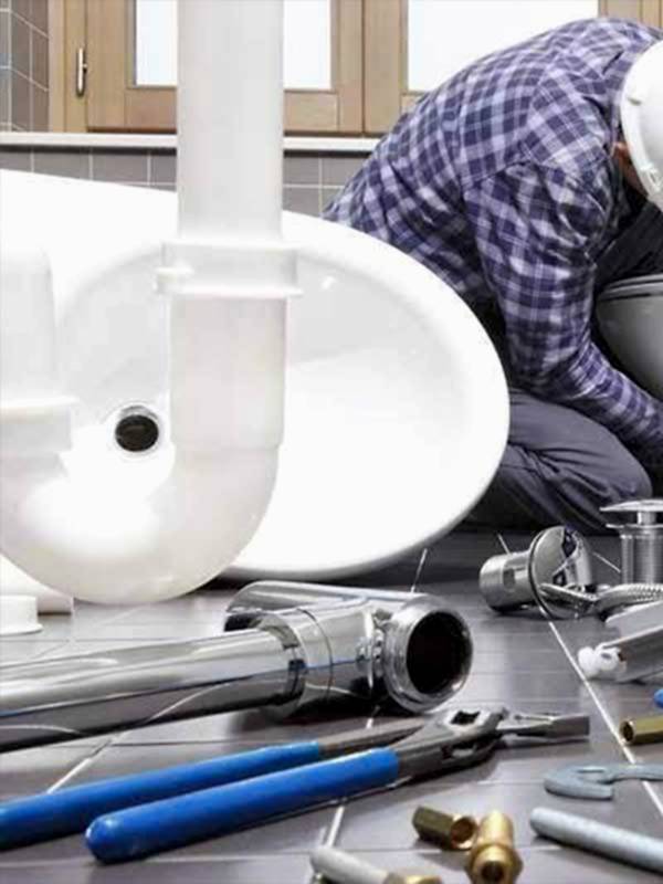 Emergency Plumbing Services in Manchester Plumber fixing a toilet, with a close-up view of pipes and various tools, provided by AD Plumbing, Heating, and Electrical.