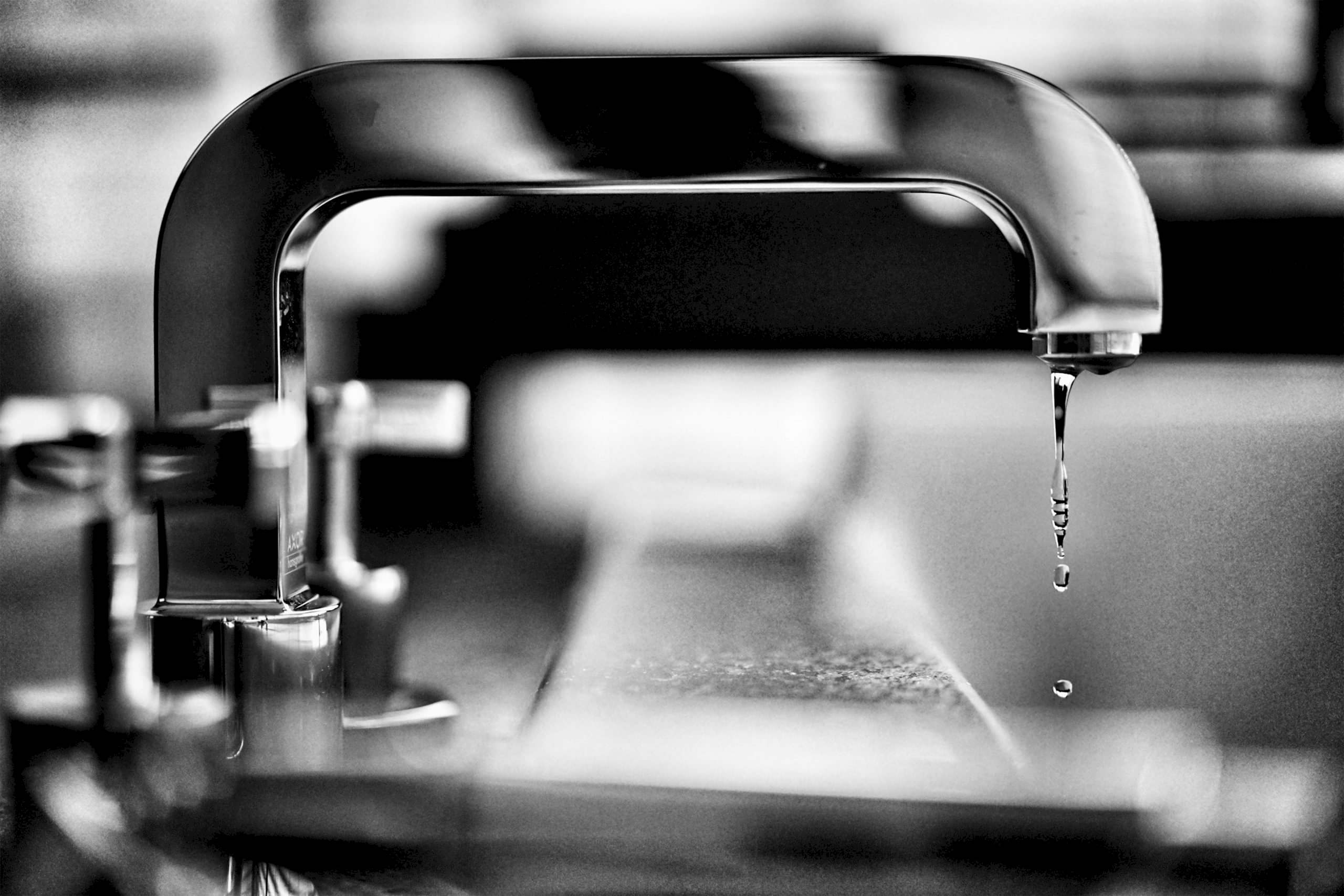 Close-up of a modern tap dripping in black and white.