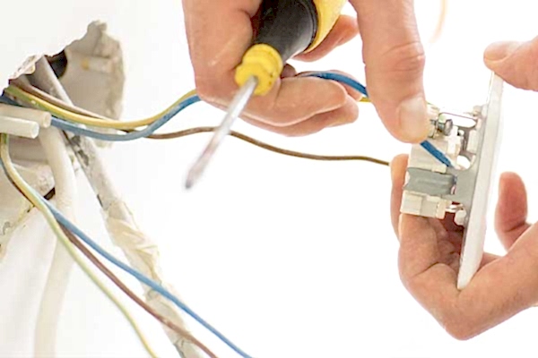 Technician's hands working on rewiring during a minor repair and unit re-fitting, provided by AD Plumbing, Heating, and Electrical.