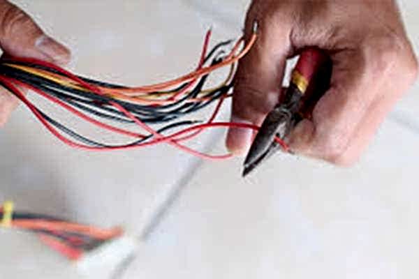 Close-up of hands rewiring electrical cables, demonstrating precise and professional electrical work by AD Plumbing, Heating, and Electrical.